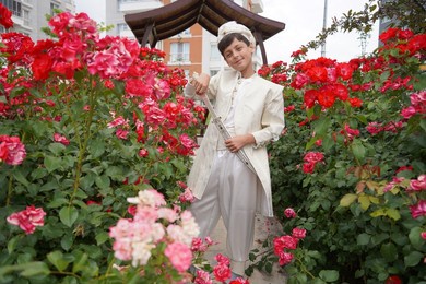 turkish boy wearing traditional clothing during a circumcision ceremony. boy standing outdoors among flowers.