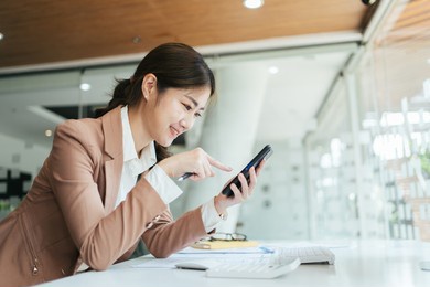 asian woman using smart phone and laptop in office.