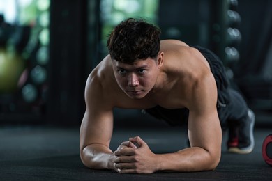 man exercising in gym. male excercise ingym. man planking on floor in gym. 