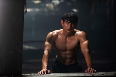 portrait of strong asian sportsman athlete in sportswear do sport training workout bodybuilding exercise in abandoned building. shirtless man bodybuilder practicing muscular build in dark place gym