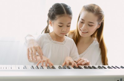 portrait of mother asian teaching her daughter playing a piano in living room at home. spend time weekend together, happy mother and daughter. creating activities to strengthen skills for children.