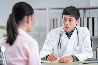 asian male doctor talking to a patient to maintain the health of the patient providing health advice to patients at the hospital