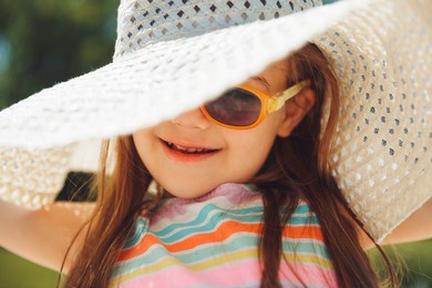 cheerful little girl with down syndrome in a summer hat on the beach.