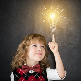 smart kid in class. happy child against blackboard. drawing light bulb. idea concept