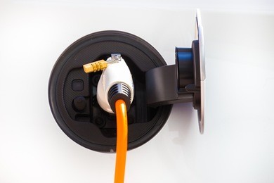 detail power supply for electric car charging.  electric car charging station. close up of the power supply plugged into an electric car being charged.