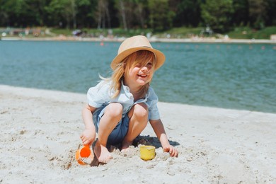 cute happy blond boy playing with beach toys on the sandy city beach.