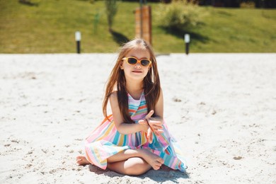 cheerful little girl with down syndrome in a summer hat on the beach.