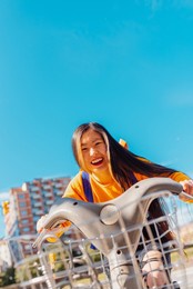 happy asian young girl riding a bicycle in the city.