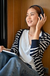 charming casual young asian woman listening to music through wireless headphones. hobbies and leisure concept