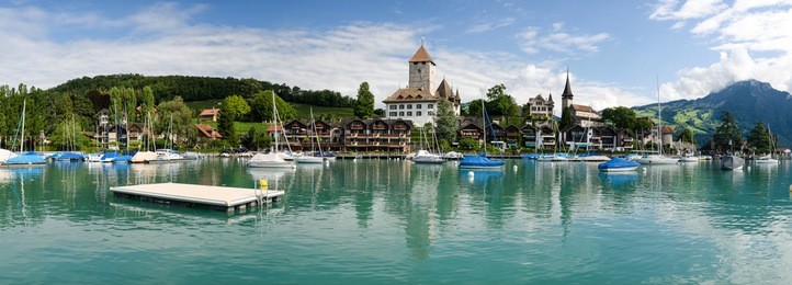 spiez castle with boats at pier and lake thun, spiez, bernese oberland, switzerland
