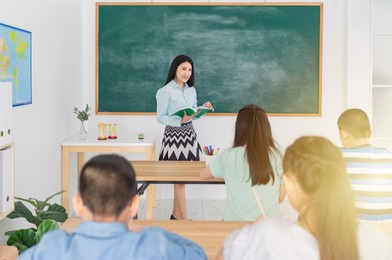light and blur people, teacher holding a book and teaching to children, asian student group studying with female teacher, students in elementary school
