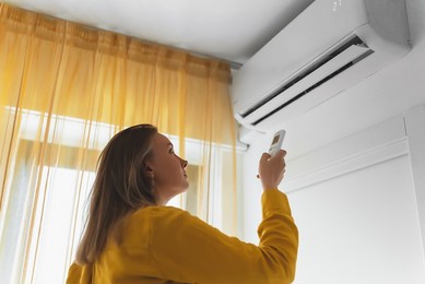 woman holding remote control aimed at the air conditioner.