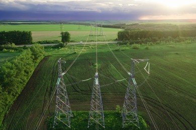 high voltage electric power tower in a green agricultural landscape at sunset