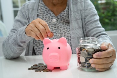 asian senior or elderly old lady woman holding counting coin money in piggy bank. poverty, saving problem  in retirement. poverty, saving problem in retirement.