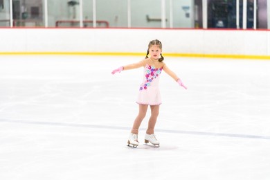 little girl practicing figure skating on an indoor ice skating rink.