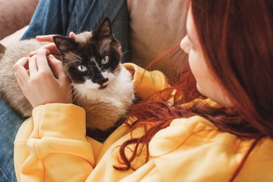happy young woman hugging and petting cat. teen girl with cat on sofa at home