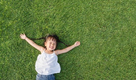 asian little girl smile and lay on grass