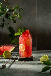 watermelon lime refreshing cocktail in modern glass (mojito, lemonade, mocktail) with fresh mint. cold summer fruit drink with beautiful dark grey textured background. selective focus, copy space.