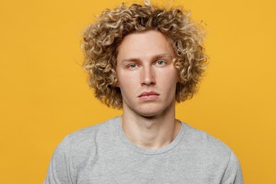 young cute calm cool blond caucasian european serious attractive man 20s he wearing basic grey t-shirt looking camera isolated on plain yellow color background studio portrait. people lifestyle concept