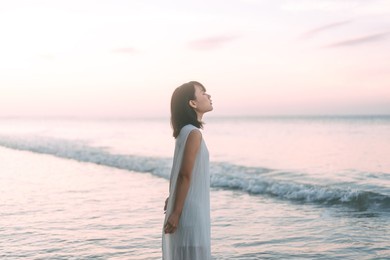 portrait of asian woman at the beach rest in the sea waves aesthetic vibes. people relax in nature concept.