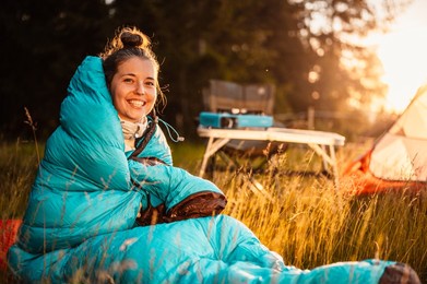 woman relaxing and lie in a sleeping bag in the tent. sunset camping in forest. mountains landscape travel lifestyle camping. summer travel outdoor adventure