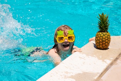 happy child playing in swimming pool. summer kids vacation. little kid boy relaxing in a pool having fun during summer vacation.