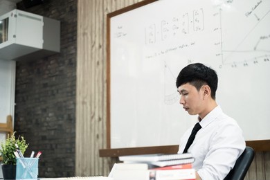 an asian male teacher at the university is preparing lessons to teach in the classroom.