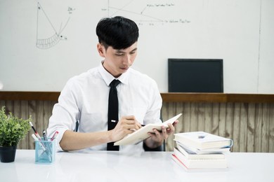 an asian male teacher at the university is preparing lessons to teach in the classroom.