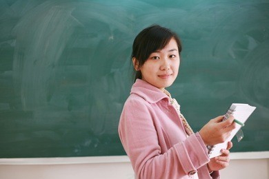 pretty young asian teacher in front of a blackboard
