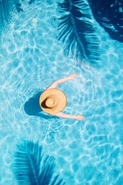top view of beautiful woman earing sunhat relaxing in swimming pool