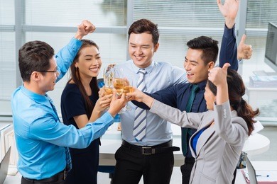 group of business people raising thumbs-up and clinking glasses