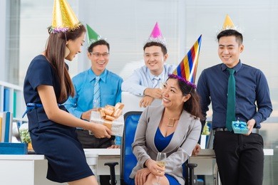 young manager giving birthday present to her colleague at the office party