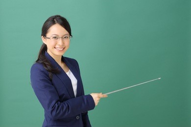 young woman with glasses pointing copy space against blackboard