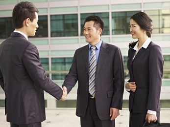 asian businesspeople shaking hands and smiling.