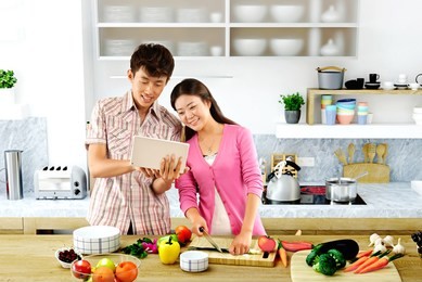 young couple cooking - men and women in the kitchen preparing food 