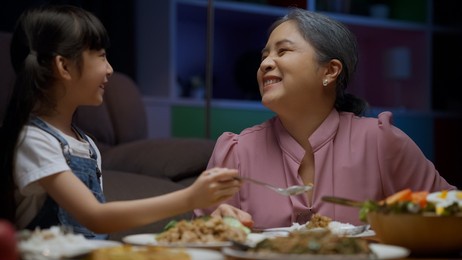 happy family spending time having dinner together at home, little girl granddaughter enjoying to eat food with grandparents, good relationship and activities at home