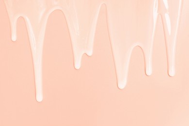 liquid shampoo dripping down on a pink background close up.