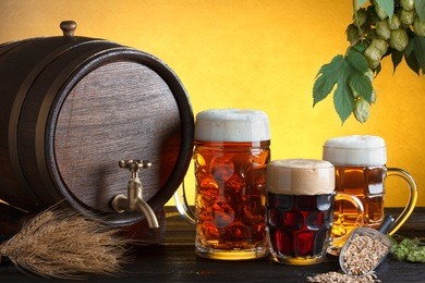 vintage beer barrel with beer glasses on wooden table with wheat bunch, hop and barley, still life with copy space