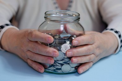 senior woman with savings in jar at table. concept of pension