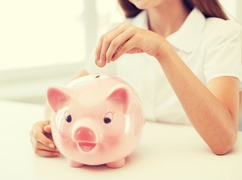 education, school and money saving concept - smiling child putting coin into big piggy bank