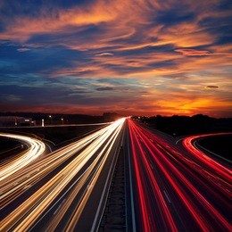 speed traffic at dramatic sundown time - light trails on motorway highway at night,  long exposure abstract urban background