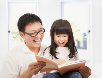 smiling  father and her daughter reading a book at home