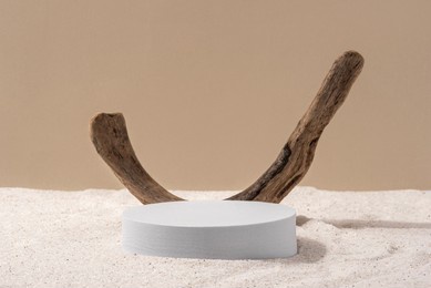 natural cosmetic background for product presentation. driftwood and white podium on the sand. front view.