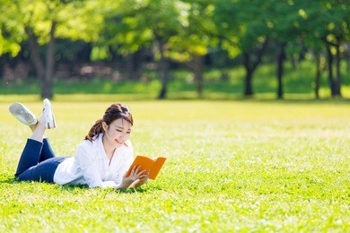 young asian woman reading book in the park