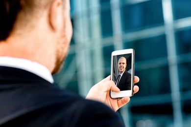 businessman having videocall on the phone with his partner on contemporary background
