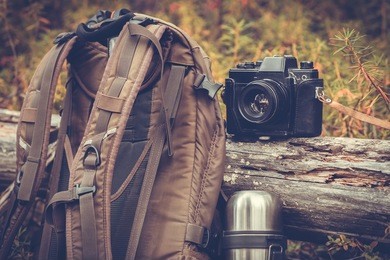 lifestyle hiking camping equipment retro photo camera backpack and thermos outdoor forest nature on background