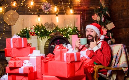 greetings from santa. bearded man sit in armchair with pile of gifts. parcels gifts will be delivered to its destination. sending gifts. santa claus residence. winter holidays. cozy home atmosphere
