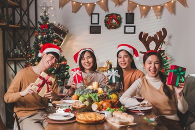 group of young asian friends cheers wine glasses to celebrate christmas eve dinner. party of asian friends enjoying drinks and celebrating. close up glasses of clinking glasses of wine with happiness.