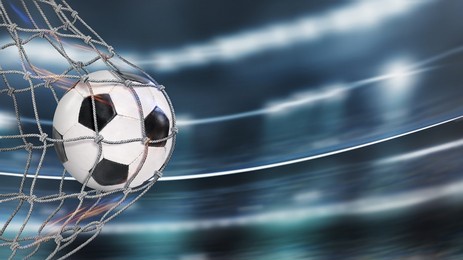  soccer ball in goal in a big stadium. soccer net