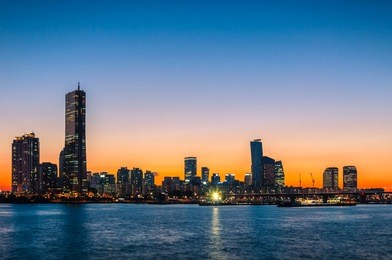the sun sets behind the skyscrapers of seoul, south korea.